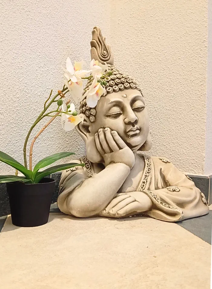 Figura de Buda apoyada junto a una orquídea