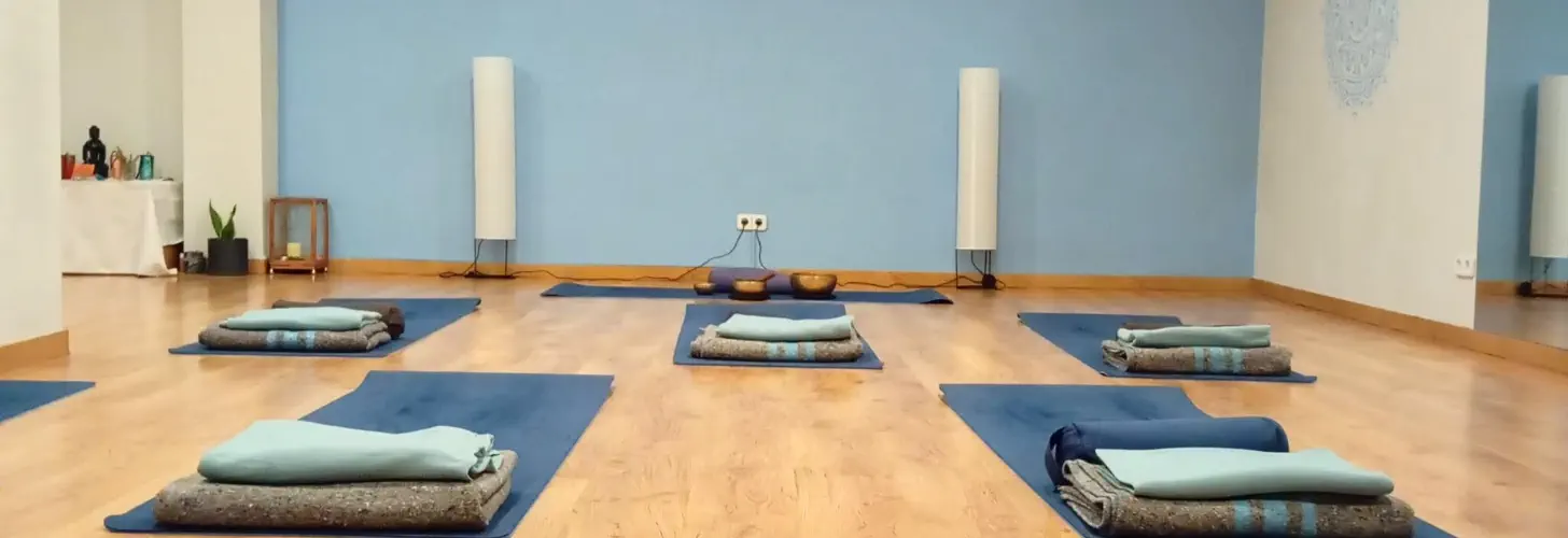 Sala de yoga de Nidhan con esterillas, mantas y cojines preparados para la clase