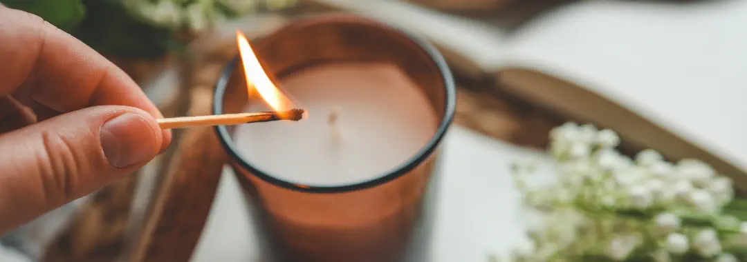 Mano encendiendo una vela con una cerilla