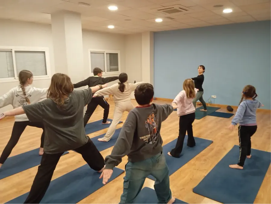Niñas y niños haciendo una postura de yoga en la sala de Nidhan